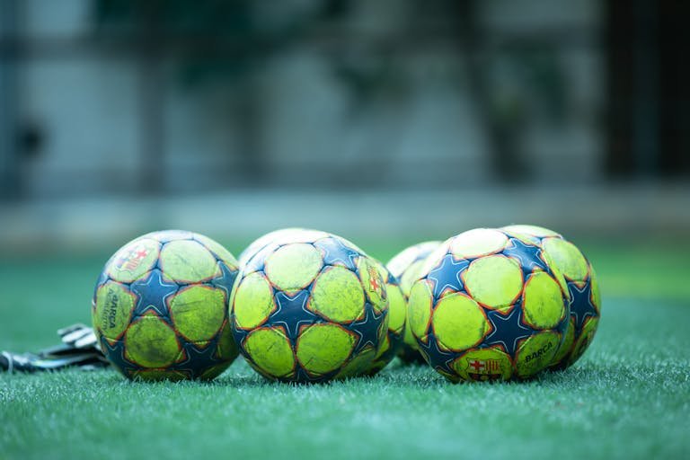 Four vibrant soccer balls resting on a green grass field.